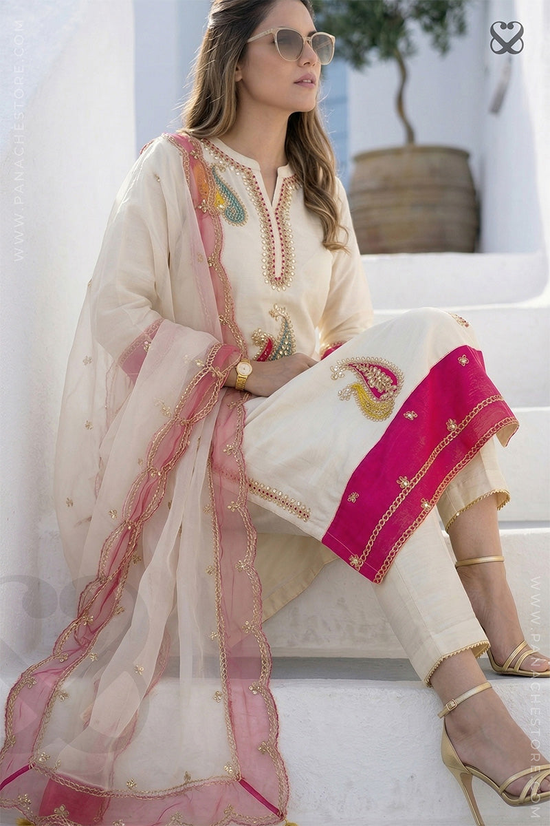 Woman in cream white slawar suit set with pink embellishments and pink dupatta standing on steps