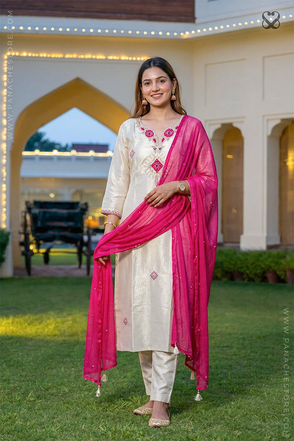 Woman in a cream salwar suit set with pink dupatta standing in garden facing front