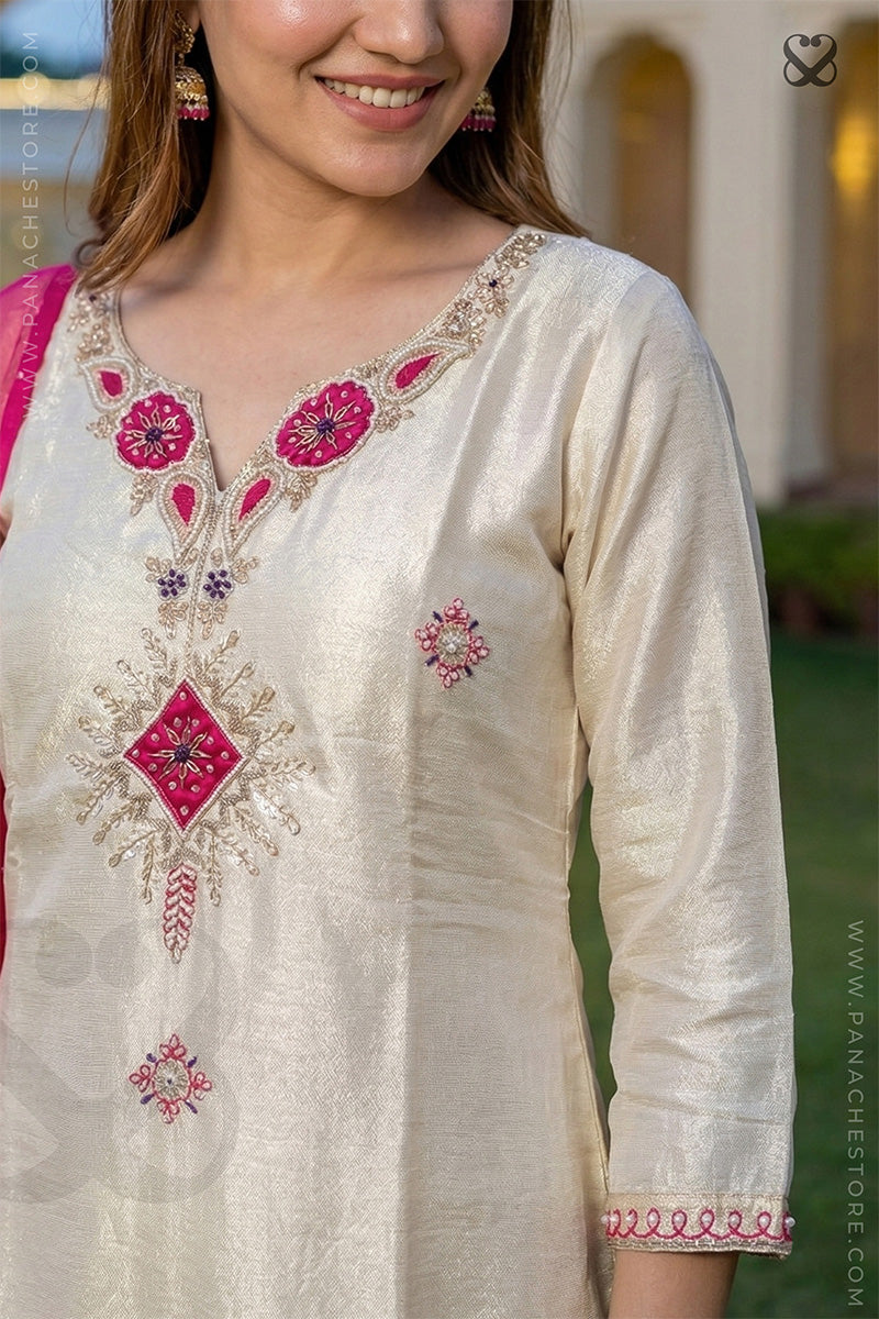 Woman wearing a cream embroidered embellished kurta with pink details, standing outdoors.