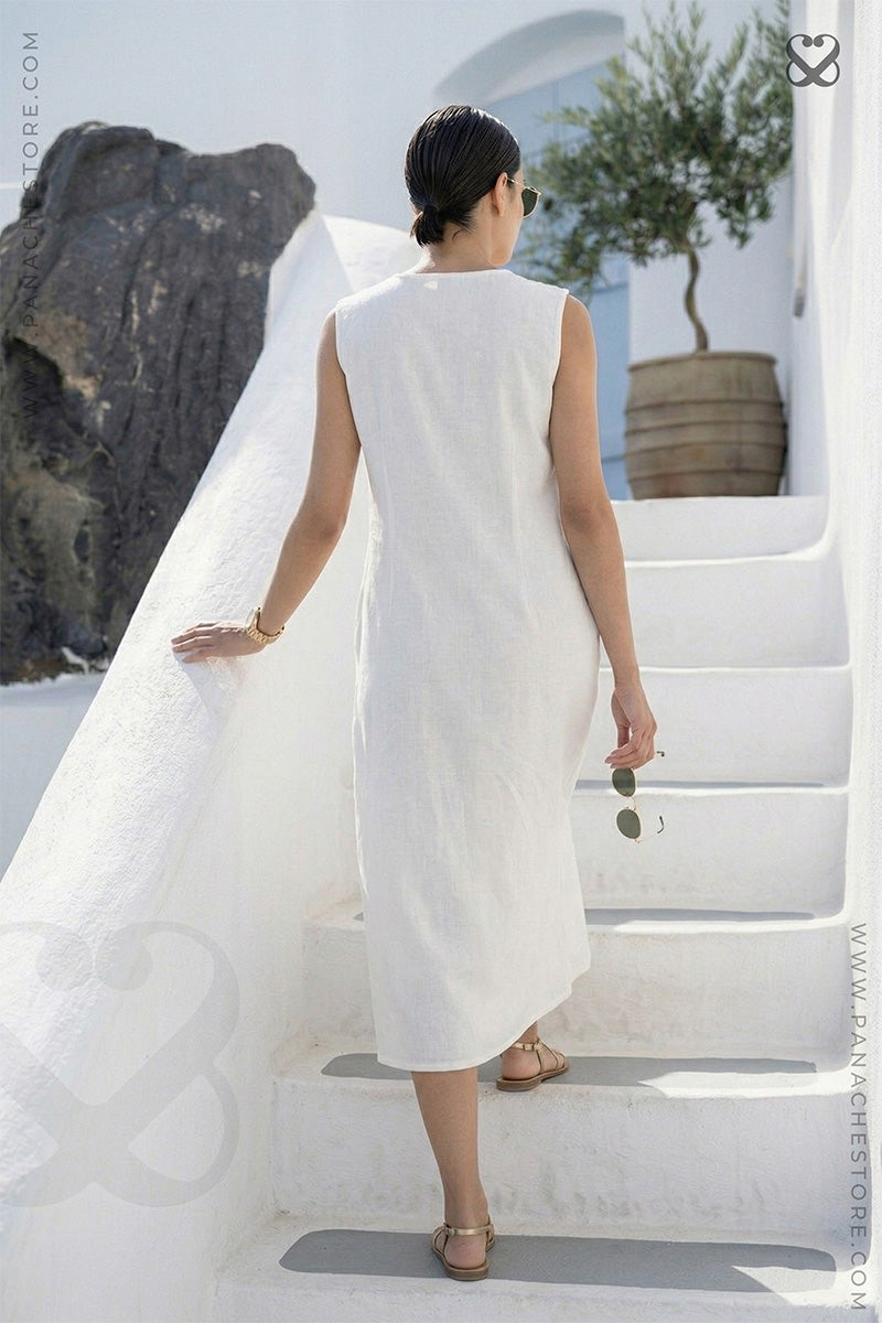 Woman in a white dress walking up a white staircase with a scenic background.