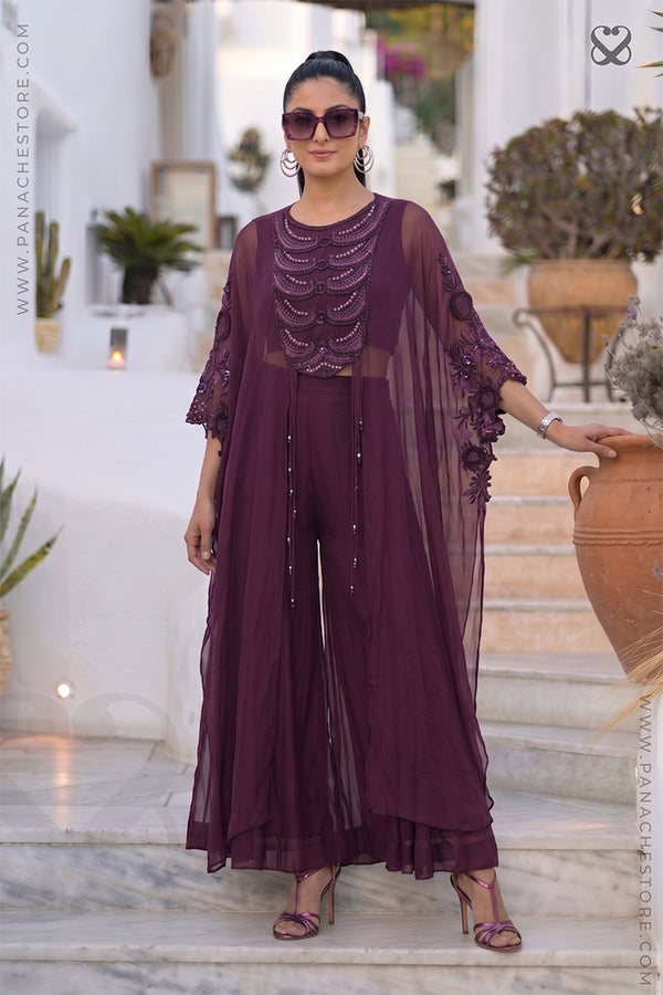 Woman in a purple-wine designer Kaftan outfit standing outdoors with decorative elements.
