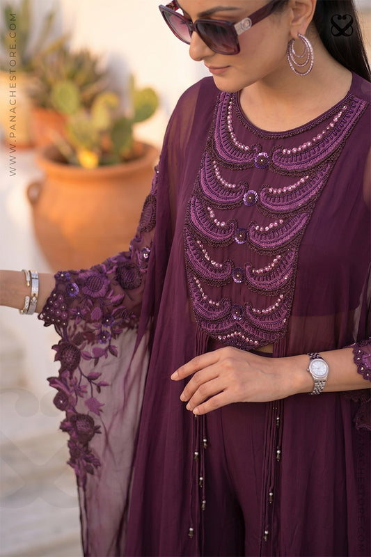 Woman wearing a maroon-wine embroidered kaftan outfit with a blurred background