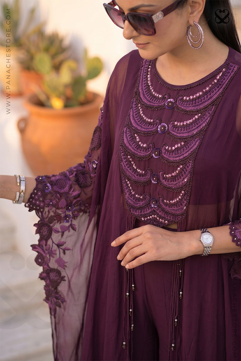 Woman wearing a maroon-wine embroidered kaftan outfit with a blurred background