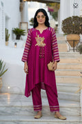 Woman wearing a magenta pink traditional kurti pant set with gold embroidery on a marble staircase.