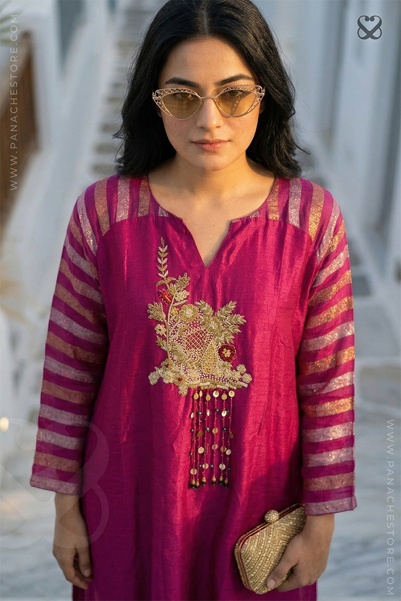 Woman wearing a pink embroidered kurta with gold details against a blurred background
