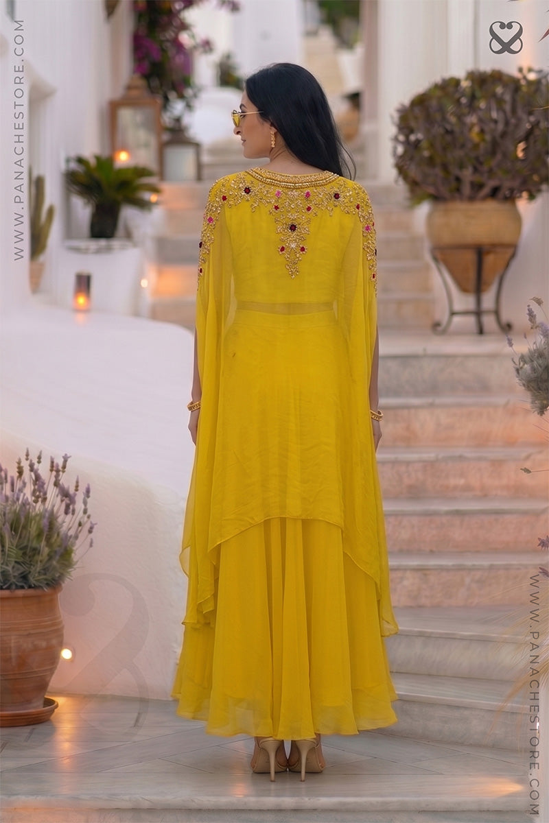 Woman wearing a designer yellow embroidered shrug outfit with zardozi and meenakari work and yellow skirt in an outdoor setting