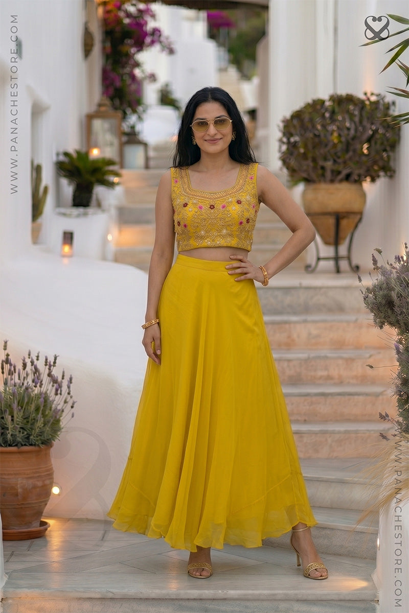 Woman wearing a designer haldi yellow embroidered blouse bustier top and yellow skirt standing on steps