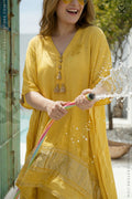 Woman in a yellow dress holding a colorful hose with water splashing around, standing outdoors.