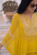 Woman wearing a yellow embroidered kaftan outfit set with sunglasses outdoors.